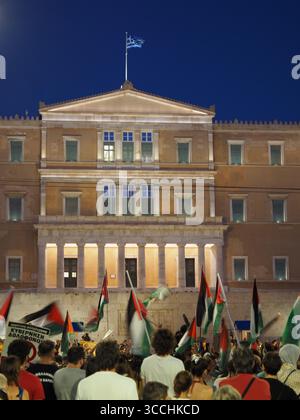 Atene, Grecia - 10 agosto 2025: Persone riunite di fronte all'edificio del parlamento greco con colonne contro il cielo blu Foto Stock
