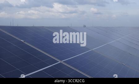 Array solari industriali sul tetto che alimentano le attività di fabbrica - integrazione di energia rinnovabile per una produzione sostenibile. Foto Stock