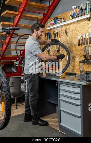 Tecnico di biciclette maschio che indossa guanti per riparare l'impianto frenante a disco su mountain bike Foto Stock