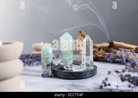 Aura. Cristalli diversi, lavanda, candele accese e Palo Santo si attaccano su un tavolo bianco Foto Stock