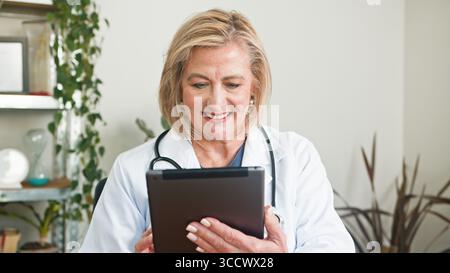 Medico donna anziano che utilizza tablet in Ufficio medico con le piante Foto Stock