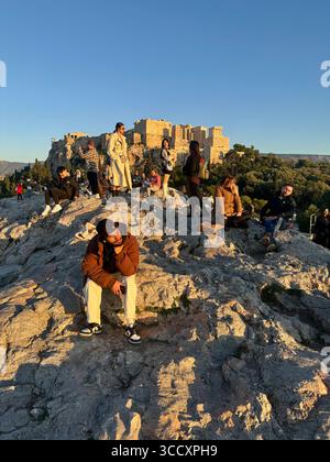I colori del tramonto dipingono il cielo sopra Atene, visto dalla collina di Areopago con l'Acropoli e il colle di Licabetto sullo sfondo. Foto Stock