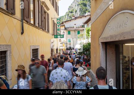 Limone sul Garda, Lombardia, Italia - 7 agosto 2025: Estate a Limone sul Garda: Affollate le stradine del centro storico. Il turismo di massa sul Lago di Garda è palpabile. L'atmosfera di vacanza incontra calore, ristrettezza e poco spazio tra facciate e negozi *** Sommer a Limone sul Garda: Menschenmengen drängen durch die enge Altstadtgasse. Der Massentourismus am Gardasee ist spürbar. Urlaubsstimmung trifft auf Hitze, Enge und wenig Platz zwischen Fassaden und Läden Foto Stock