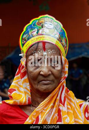 Narayanganj, Bangladesh - 23 agosto 2019: Veduta di una donna con pelle intemprata, adornata da un vivace copricapo giallo e rosso, che incarna una presenza serena e dignitosa. Foto Stock