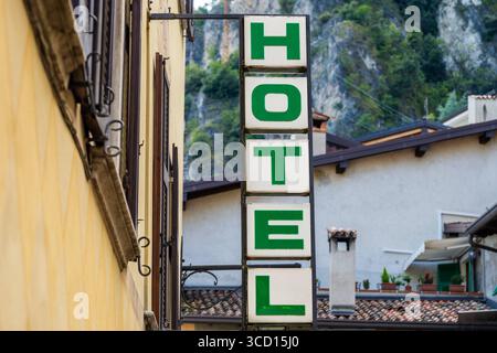 Italia 7 agosto 2025: Un cartello verde con la parola HOTEL è appeso sulla facciata di un edificio in un vicolo della città vecchia in una località turistica. Segna l'alloggio e mostra agli ospiti la strada per raggiungere le loro camere e il banco della reception un classico segno delle operazioni alberghiere. *** Ein Grünes Hotelschild mit HOTEL hängt an der Hausfassade einer Altstadtgasse im Urlaubsort. Es markiert die Unterkunft und zeigt Gästen den Weg zu Zimmern und Rezeption ein klassisches Zeichen des Hotelbetriebs. Foto Stock