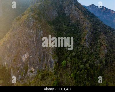 Spettacolare veduta aerea della scogliera di calcare e della fitta foresta al tramonto nelle montagne vicino a Muang Ngoy, Laos Foto Stock