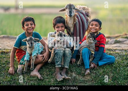 Bogura, Bangladesh - 06 gennaio 2023: Si dispiega la vista dei bambini che emettono i loro agnelli tra la luce soffusa del mattino, un arazzo di gioia giovanile e fascino rurale. Foto Stock