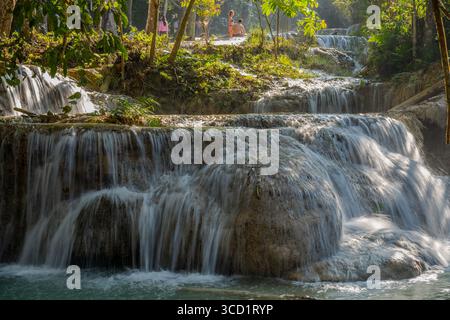 Visitatori che si godono le cascate di Kuang si a più livelli che scorrono attraverso la giungla tropicale vicino a Luang Prabang, Laos Foto Stock