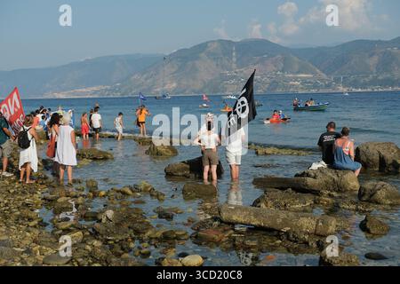 I dimostranti accolgono con favore l'arrivo delle tradizionali barche da pesca conosciute come feluche, navigando con le bandiere "No Ponte". La protesta fa parte del movimento che si oppone alla costruzione del ponte sullo stretto di Messina. Foto Stock