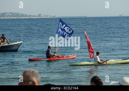 I dimostranti accolgono con favore l'arrivo delle tradizionali barche da pesca conosciute come feluche, navigando con le bandiere "No Ponte". La protesta fa parte del movimento che si oppone alla costruzione del ponte sullo stretto di Messina. Foto Stock