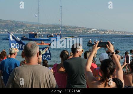 I dimostranti accolgono con favore l'arrivo delle tradizionali barche da pesca conosciute come feluche, navigando con le bandiere "No Ponte". La protesta fa parte del movimento che si oppone alla costruzione del ponte sullo stretto di Messina. Foto Stock
