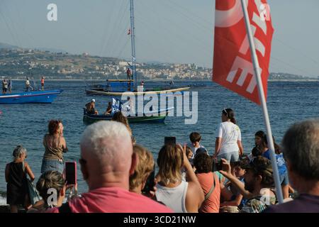 I dimostranti accolgono con favore l'arrivo delle tradizionali barche da pesca conosciute come feluche, navigando con le bandiere "No Ponte". La protesta fa parte del movimento che si oppone alla costruzione del ponte sullo stretto di Messina. Foto Stock