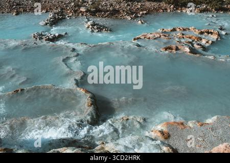 Vista delle acque termali azzurre che si infrangono su formazioni rocciose di travertino, creando un paesaggio etereo e surreale, Saturnia, Toscana, Italia. Foto Stock