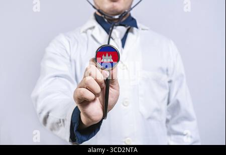 Mani del medico che tengono lo stetoscopio con la bandiera della Cambogia. Concetto di salute e assistenza in Cambogia Foto Stock