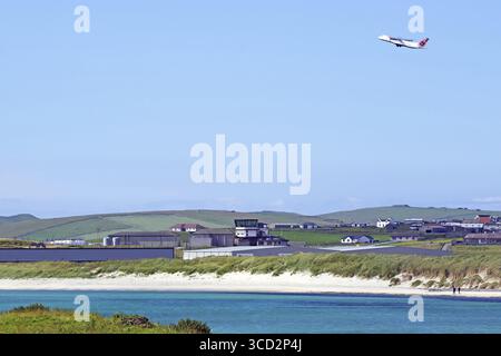 Aeroplano che decolla dalla costa con hangar e terra verde, Sumburgh Head, Isole Shetland, Scozia, Regno Unito Foto Stock