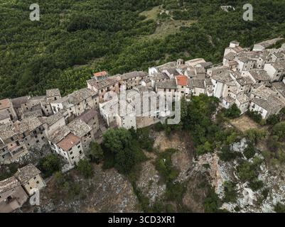 Vista aerea di antiche abitazioni aggrappate alla ripida collina, un arazzo di pietra e tetti di terracotta intemprati tra il verdeggiante abbraccio del Foto Stock