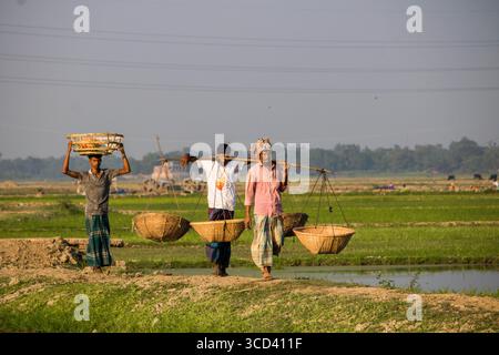 18 dicembre 2022 - il vasaio del popolo del Bangladesh porta i suoi vasi di ceramica di terra per la vendita nel mercato locale attraverso una strada del villaggio oggi. Foto Stock