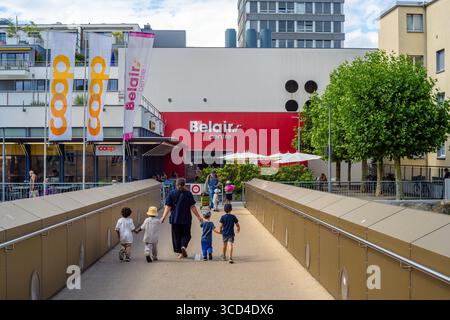 Yverdon les Bains, Svizzera - 24 luglio 2025: Una famiglia che cammina verso il Belair Centre, un complesso commerciale. La scena presenta un'architettura moderna Foto Stock