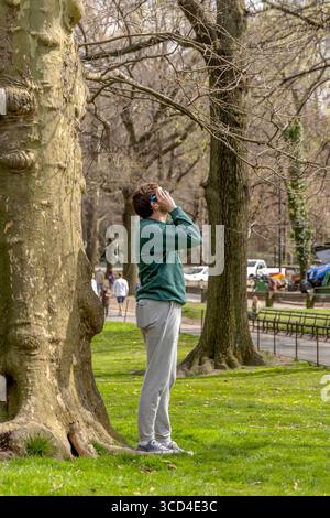 Vista ad angolo basso della donna che osserva l'eclissi solare dell'aprile 2024 a Central Park, Manhattan, New York, USA, catturando la vita urbana e all'aperto Foto Stock