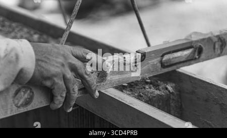 Una livella a bolla d'aria si appoggia sul calcestruzzo per garantire l'uniformità della superficie, un passo essenziale per mantenere precisione e qualità nei lavori di costruzione Foto Stock