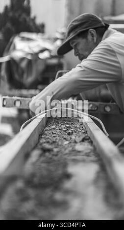 Una livella a bolla d'aria si appoggia sul calcestruzzo per garantire l'uniformità della superficie, un passo essenziale per mantenere precisione e qualità nei lavori di costruzione Foto Stock