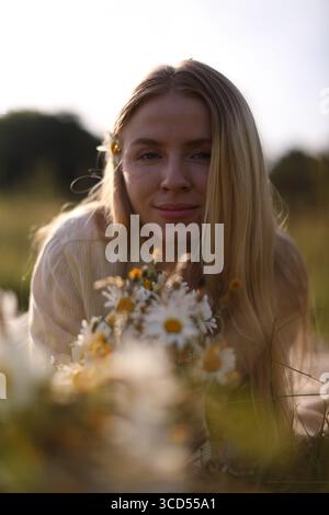 Bella donna con fiori selvatici nel prato durante il giorno di sole Foto Stock