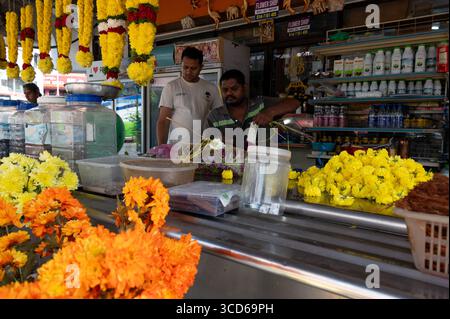 Una fila di colorate ghirlande di fiori di Marigold in vendita e altri prodotti indiani in Chulia Street nel quartiere di Little India a Georgetown, capitale Foto Stock
