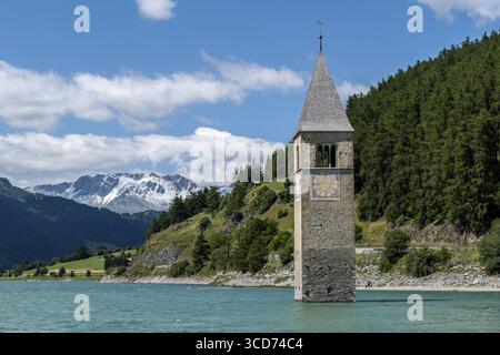 La torre della chiesa sommersa nel lago di Resia sullo sfondo alpino Foto Stock