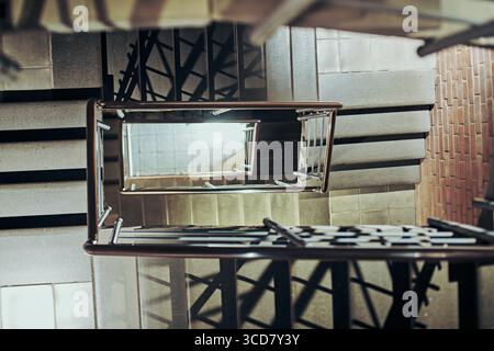 Scala a chiocciola vista dall'alto a Nizhny Novgorod. Elementi in metallo e cemento creano ripetizioni geometriche. L'illuminazione soffusa aggiunge profondità e visibilità Foto Stock