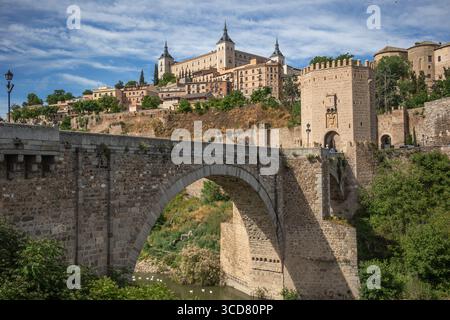 Vista soleggiata del Puente de Alcántara e del Alcázar di Toledo in Spagna. La Fortificazione di pietra sulla collina dell'UNESCO. Patrimonio culturale in Europa. Foto Stock