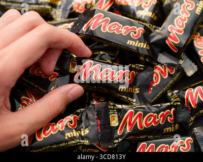 Tambov, Federazione Russa - 08 agosto 2025 persona che prende a mano la tavoletta di cioccolato Mars minis da un mucchio di altre tavolette di cioccolato Mars. Foto Stock