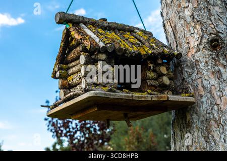 Primo piano di una casa per uccelli rustica fatta a mano, fatta di ramoscelli, appesa su un albero in un ambiente naturale all'aperto con sfondo blu del cielo. Foto Stock