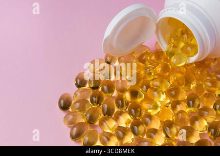 Olio Vitaminen Omega 3 in capsule su sfondo rosa. Molte pillole mediche in bottiglia di plastica bianca. Concetto di assistenza sanitaria. Foto Stock