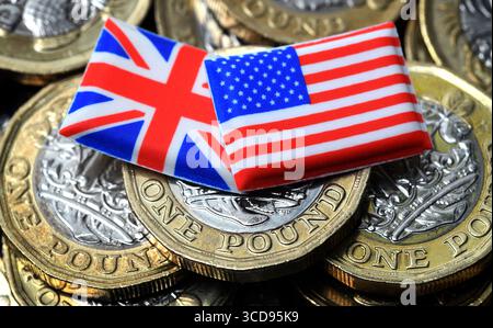 LE BANDIERE BRITANNICHE E AMERICANE CON MONETE DA UNA STERLINA RIPAGANO I TASSI DI CAMBIO DELLA STERLINA DEL DOLLARO DELL'ECONOMIA ETC UK Foto Stock