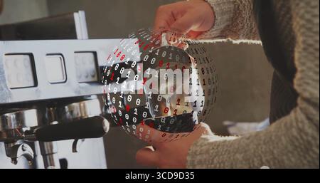 Il barista indossa un maglione grigio che monta il latte con la lancia del vapore in un bar, con sovrapposizione del codice binario Foto Stock