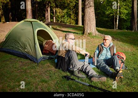 Coppia caucasica senior che si rilassa all'aperto vicino alla tenda durante il campeggio Foto Stock