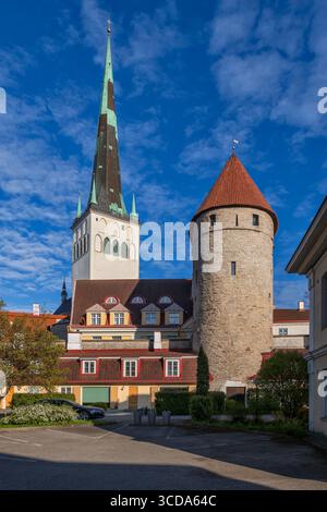 Città vecchia nella città di Tallinn in Estonia. Torre e guglia della Chiesa di Sant'Olaf, condomini e torre in pietra, parte delle mura medievali della città fortificata Foto Stock