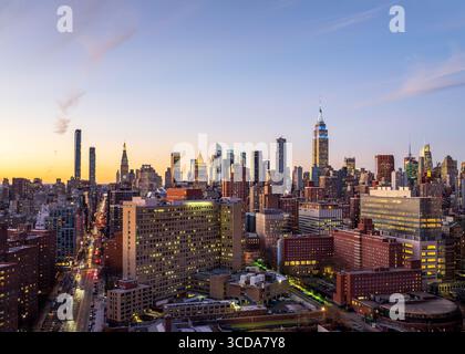 Vista aerea dei grattacieli che piergono il cielo crepuscolo mentre l'Empire State Building si erge alto tra l'arazzo urbano di New York, New York, Stati Uniti. Foto Stock