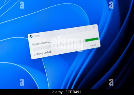 Poznan, Polonia - 9 agosto 2025: Finestra di aggiornamento della piattaforma Steam visualizzata in modo prominente su un desktop blu vivace, che illustra la necessità di appl Foto Stock