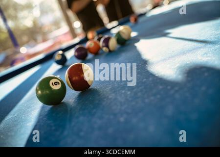 Le colorate palle da biliardo si trovano su un tavolo da biliardo blu, suggerendo una partita in corso, con l'attenzione sulla palla numero 6 Foto Stock
