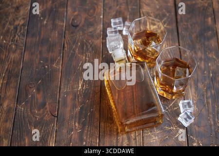 Bottiglia di whisky con due bicchieri posti su un tavolo rustico in legno Foto Stock