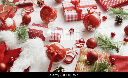 Piccoli rami di conifere e bella baubles giacente sul bianco sullo sfondo di legname che giace nei pressi di adorabili regali di Natale Foto Stock