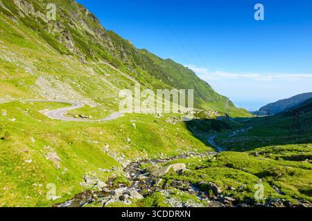 paesaggio con strada transfagarasan in estate. viaggi in romania. vista panoramica della valle con ripide colline rocciose e ruscelli d'acqua in una mattinata di sole. alpino Foto Stock