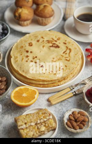 Vari ingredienti per la colazione sono stati messi su un tavolo di pietra. Con pancake, muffin, frutta fresca, cupcake, caffè nero in tazza. Posizione piatta. Vista dall'alto Foto Stock