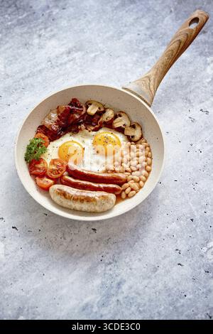 Colazione inglese completa con salsicce, pomodori alla griglia, funghi, uova, pancetta fagioli e pane al forno. Vista dall'alto Foto Stock