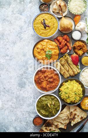 Composizione della cucina indiana in ciotole di ceramica su tavola di pietra. Tikka masala, pollo al burro, Nilgiri, kebab seekh, riso, cipolla Bhajia, paneer, samosa Foto Stock