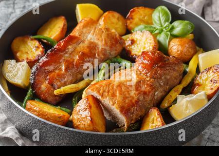 Filetto di maiale all'aglio al limone al forno con fagioli francesi e patate novelle da vicino in una padella sul tavolo. Orizzontale Foto Stock