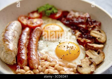 Colazione inglese completa con salsicce, pomodori alla griglia, funghi, uova, pancetta fagioli e pane al forno. Vista dall'alto Foto Stock