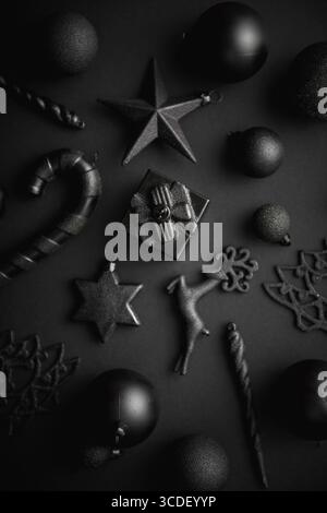 Composizione semplice e minimalista natalizia in nero opaco. Regali di Natale, decorazioni su sfondo nero. Disposizione piatta, vista dall'alto Foto Stock