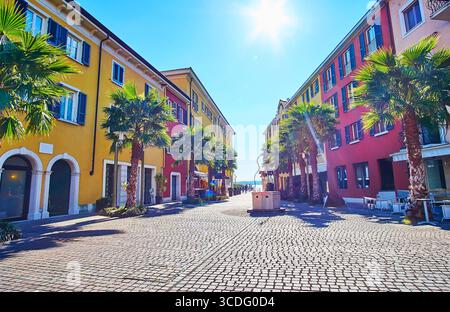 Il cielo soleggiato sopra la panoramica piazza pedonale di Piazza Castello con linee di palme verdi e case colorate, Sirmione, Italia Foto Stock